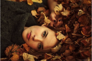 Woman staring intensely lying in a pile of leaves outdoors