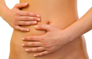 Close-up of a woman's hands touching her flat stomach