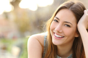 Young woman with long brown hair smiling outdoors