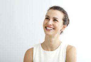 Woman with brown hair in a bun looking upward and smiling