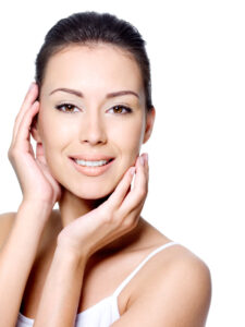 Woman with bright, clear skin smiling while gently touching her face