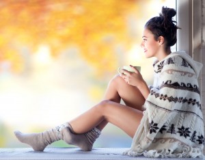 Relaxed, smiling woman holding a mug and wearing a sweater and socks
