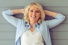 Mature woman with blonde hair resting her hands on the back of her head