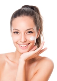 Joyful woman with skincare cream on her cheek smiling