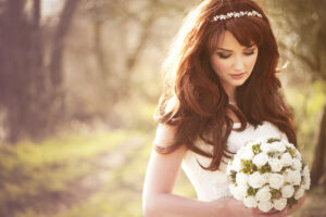 Bride with long red hair outdoors holding a bouquet