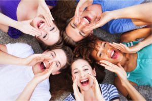 Group of five people lying on the ground smiling