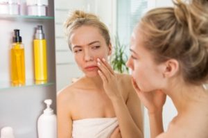 Woman examining her skin in the bathroom mirror