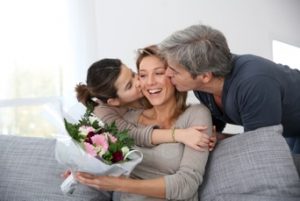Mother receiving flowers from her husband and young daughter