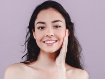 woman smiling and touching her cheek