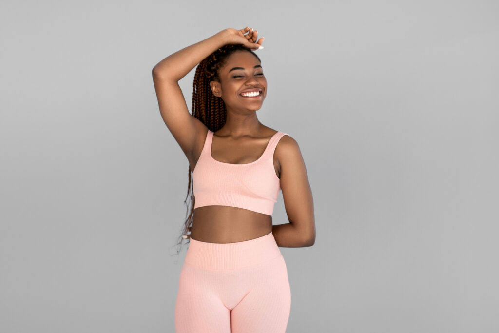 Fit woman in cute pink white workout attire feels good after CoolSculpting.