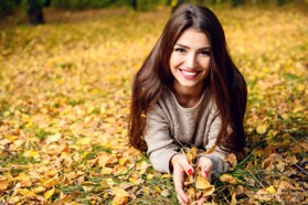 woman laying in grass and leaves smiling