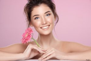 Woman smiling and holding a pink flower