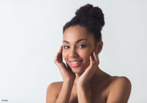 Woman with smooth skin smiling and touching her cheeks