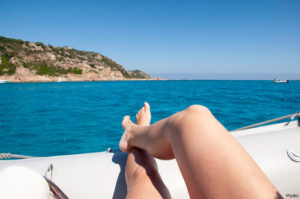 person laying on the bow of a boat overlooking the water