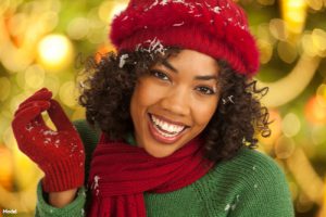 Joyful woman in a red knit hat, scarf, gloves and a green sweater smiling