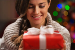 Smiling woman in a gray sweater holding a red gift box