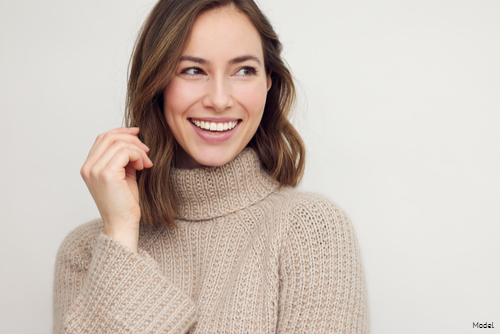 Woman with short brown hair in a cozy turtleneck sweater smiling