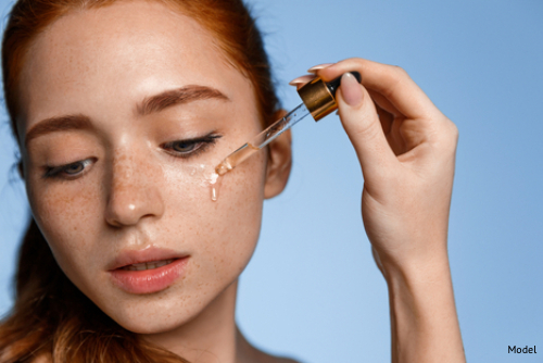 Young woman applying a skincare serum to her face