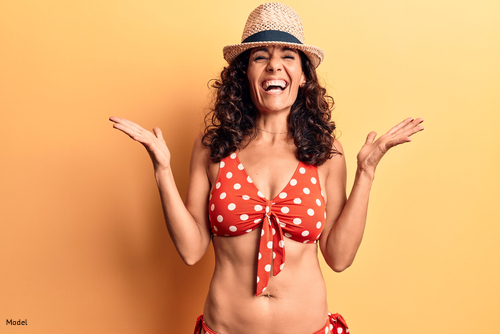 Happy, confident woman smiling in a beach hat and a two-piece polka dot bikini