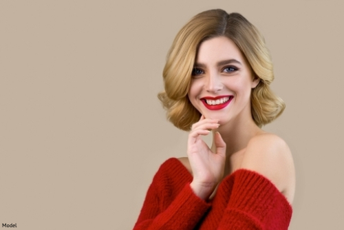 woman with a blonde bob smiling in a red sweater